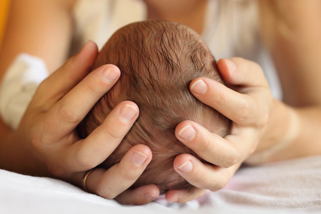 niño entre manos osteopatia bebes